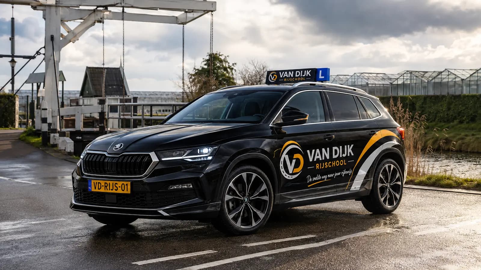 Zwarte Van Dijk Rijschool-lesauto op een rustige weg bij Kwintsheul